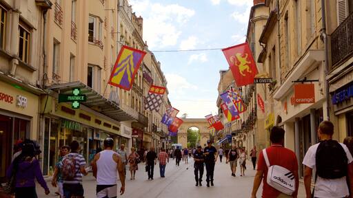 Una calle animada bordeada de tiendas y cafés, decorada con banderas y banderines de colores.