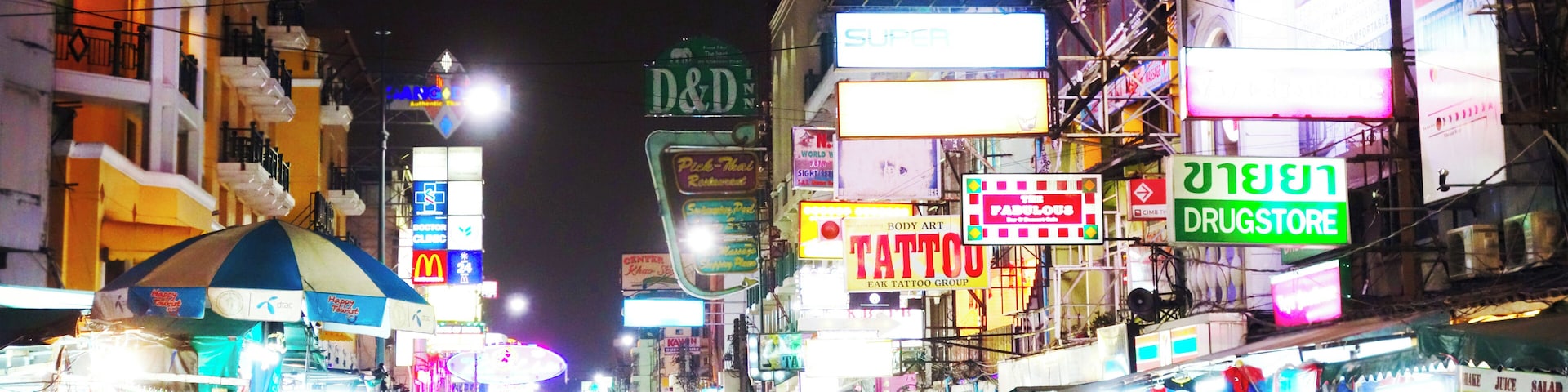 Khao San Road in Bangkok at night: You see many tourists walking around, having fun and enjoying their vacation
