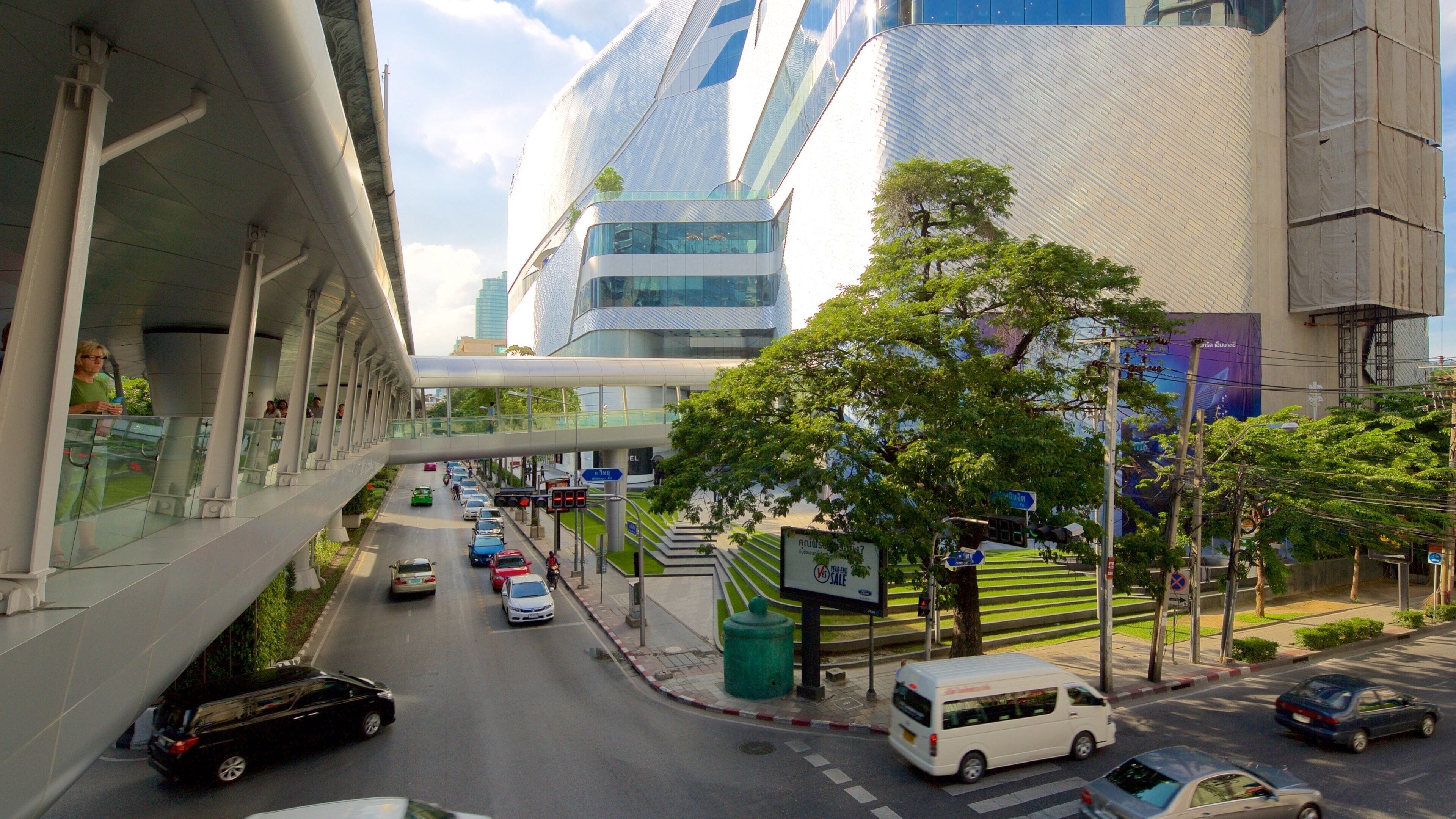 A modern urban street with cars, a bus, and a pedestrian overpass.