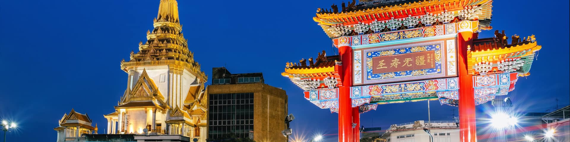 A brightly lit pagoda and traditional gate at dusk.