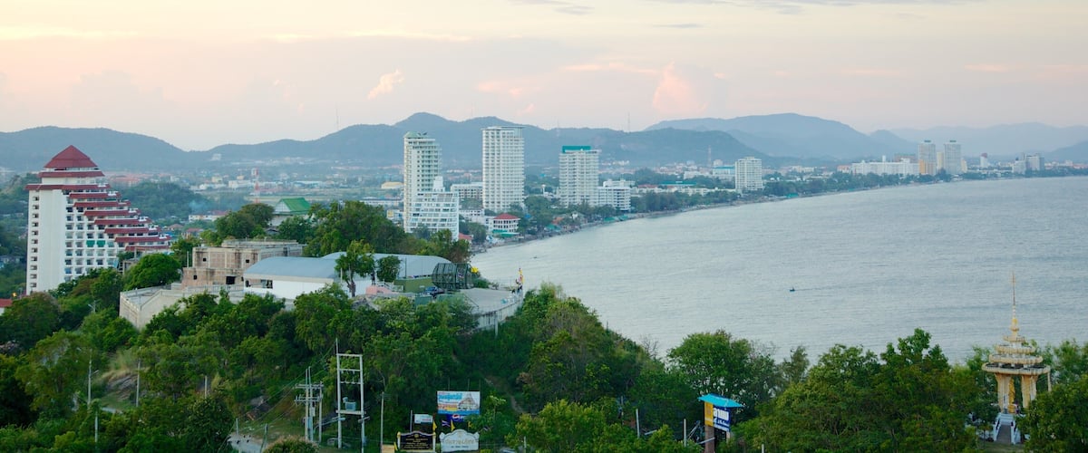 A coastal cityscape with a prominent tower, a river, and mountains in the background.