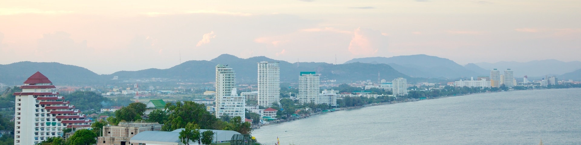 A coastal cityscape with a prominent tower, a river, and mountains in the background.
