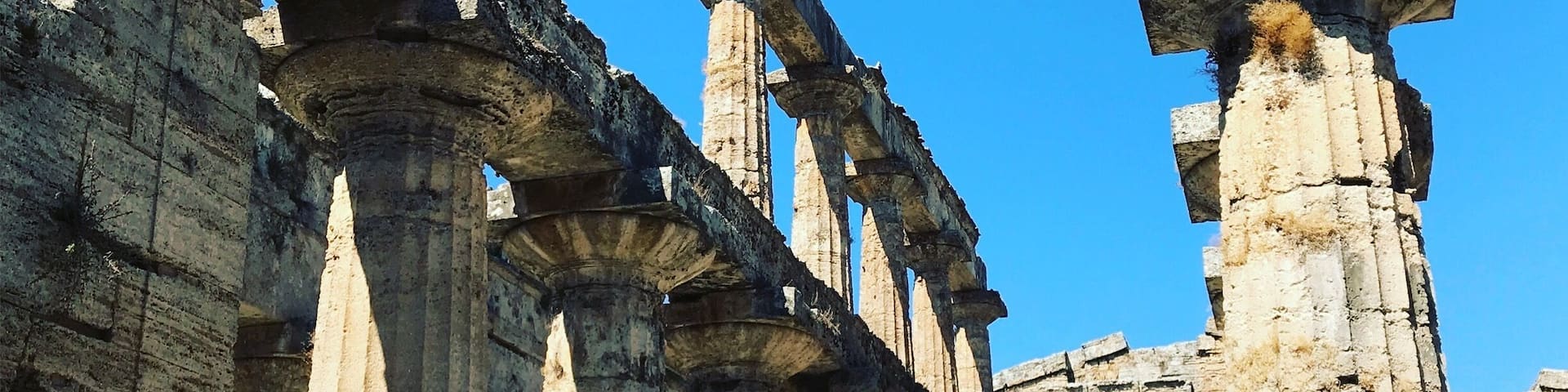 Columnas de piedra antiguas y una gran estructura pétrea en un sitio histórico.