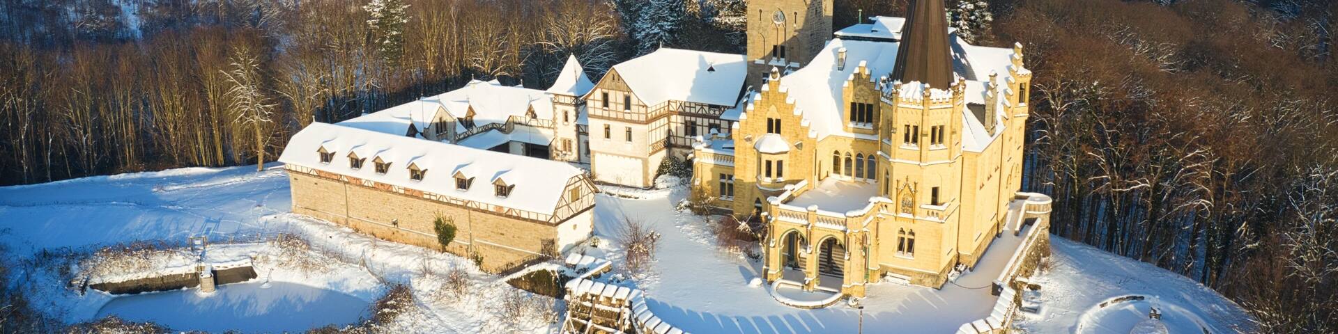 Luftaufnahme von Schloss Rothestein im Winter bei Bad Sooden-Allendorf im Werratal bei Sonnenuntergang und leichtem Schneefall