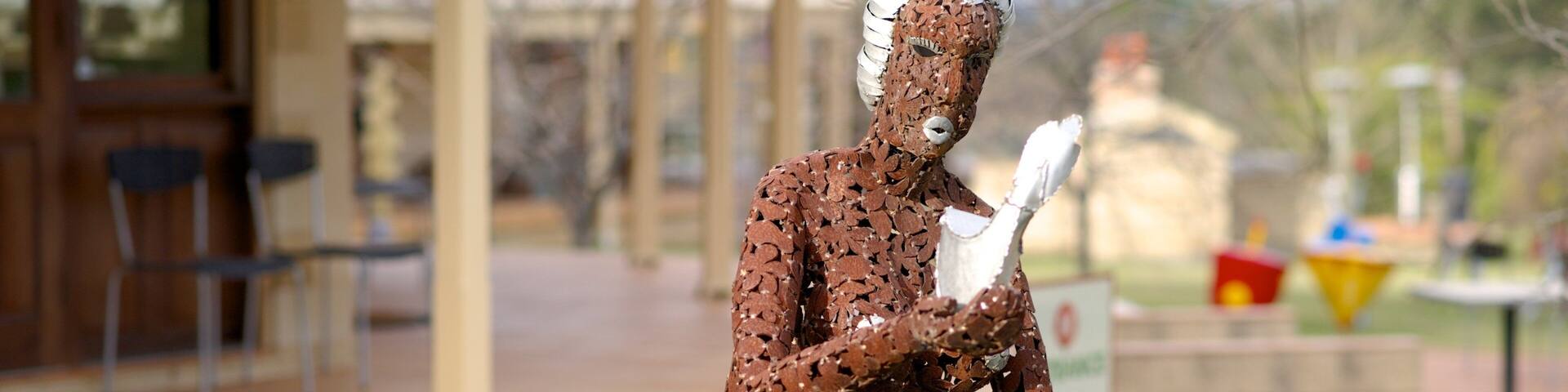 A sculpture of a woman in a brown dress riding a bicycle.