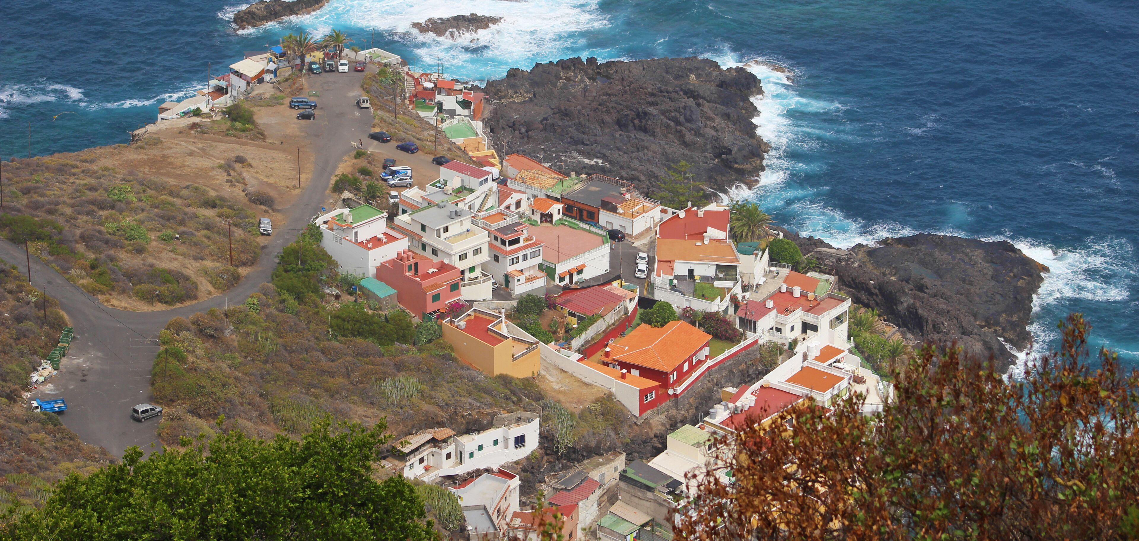 A coastal village with red-roofed houses, rocky cliffs, and the ocean.