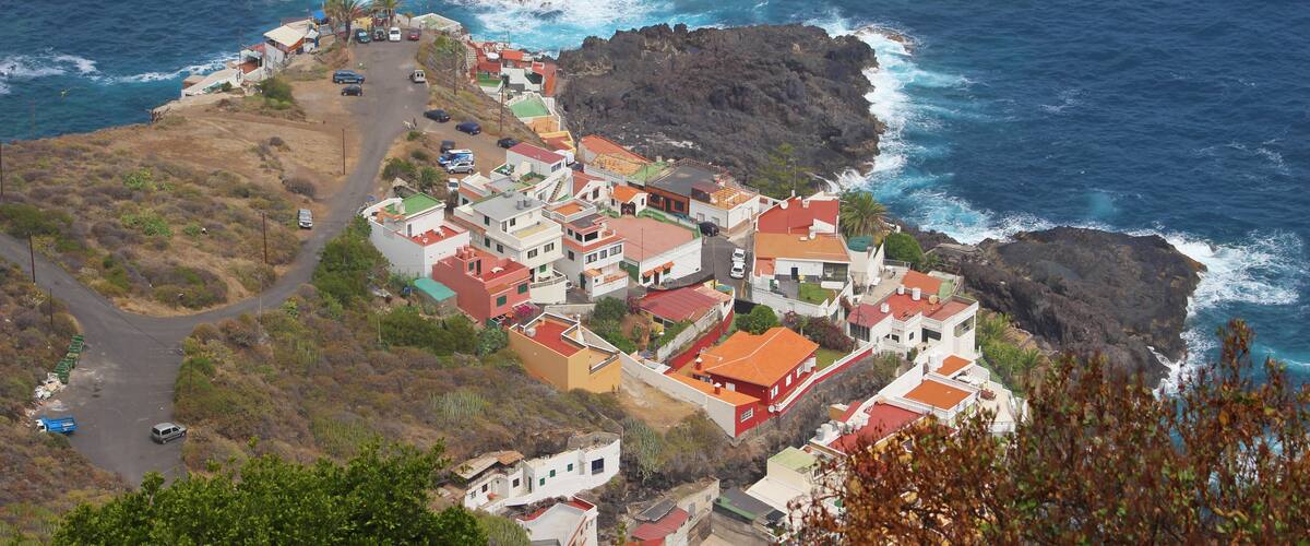 A coastal village with red-roofed houses, rocky cliffs, and the ocean.