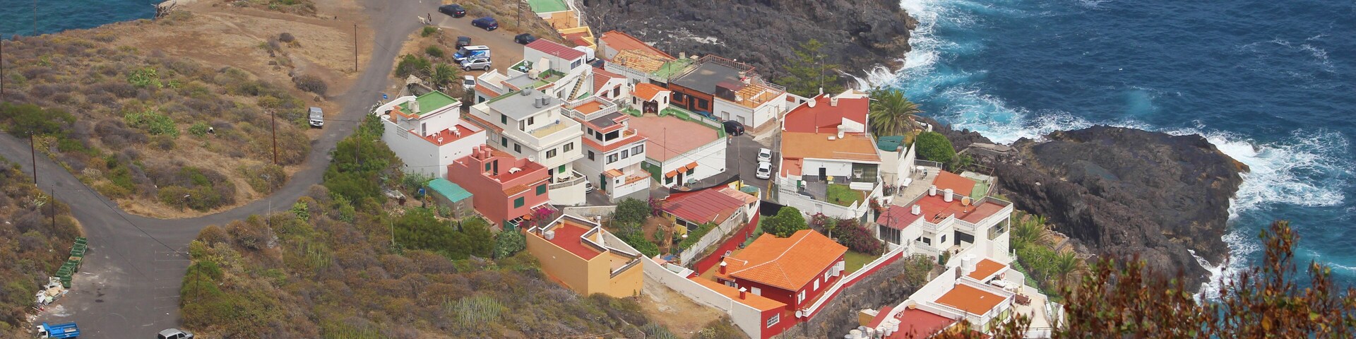 A coastal village with red-roofed houses, rocky cliffs, and the ocean.