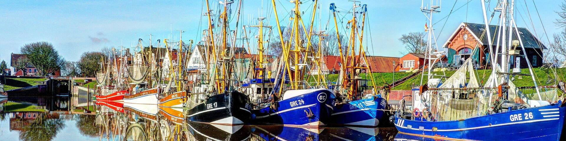 A harbor with multiple fishing boats docked, their names and numbers visible.