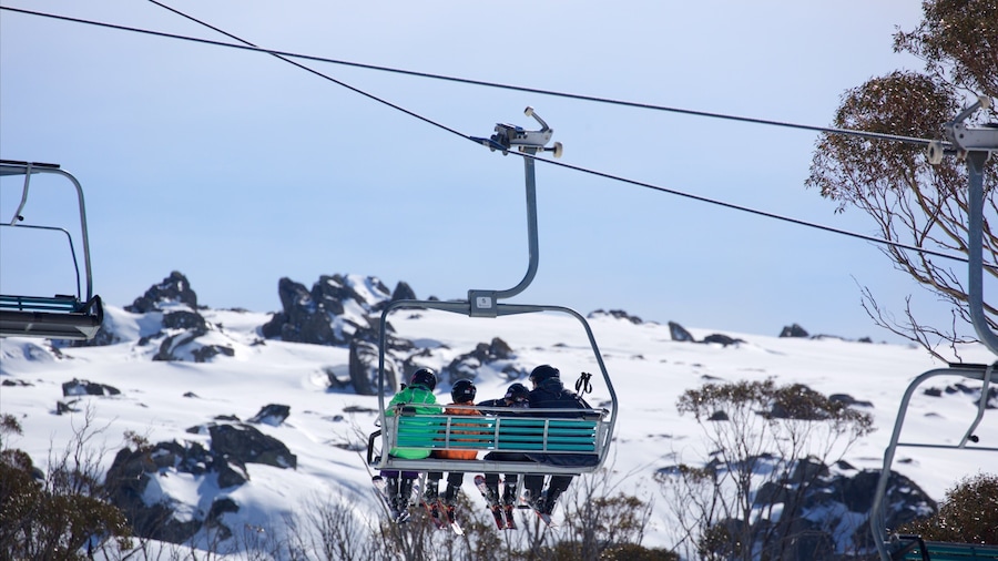 Snowy Mountains featuring a gondola and mountains as well as a family