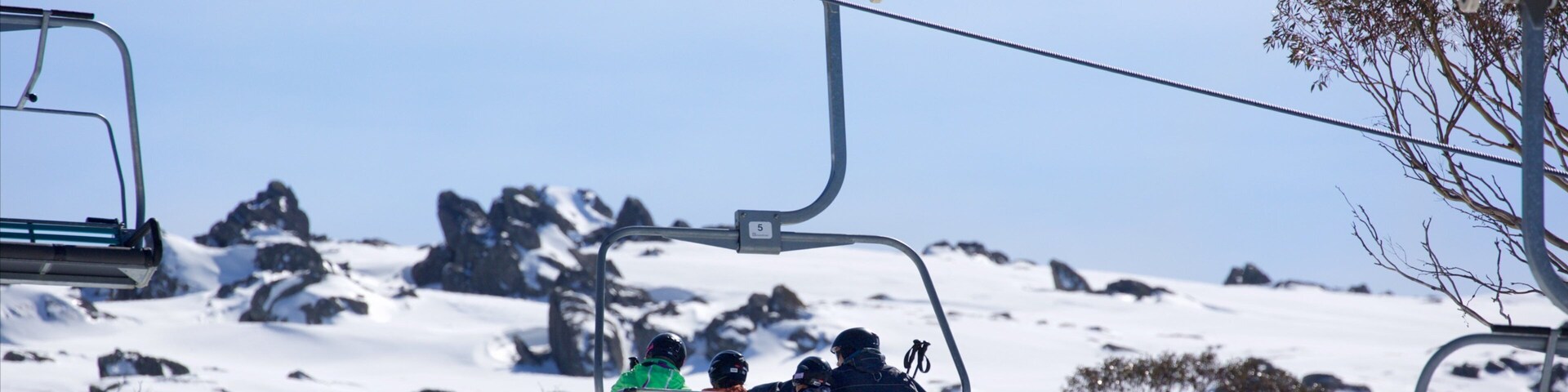 Snowy Mountains featuring a gondola and mountains as well as a family
