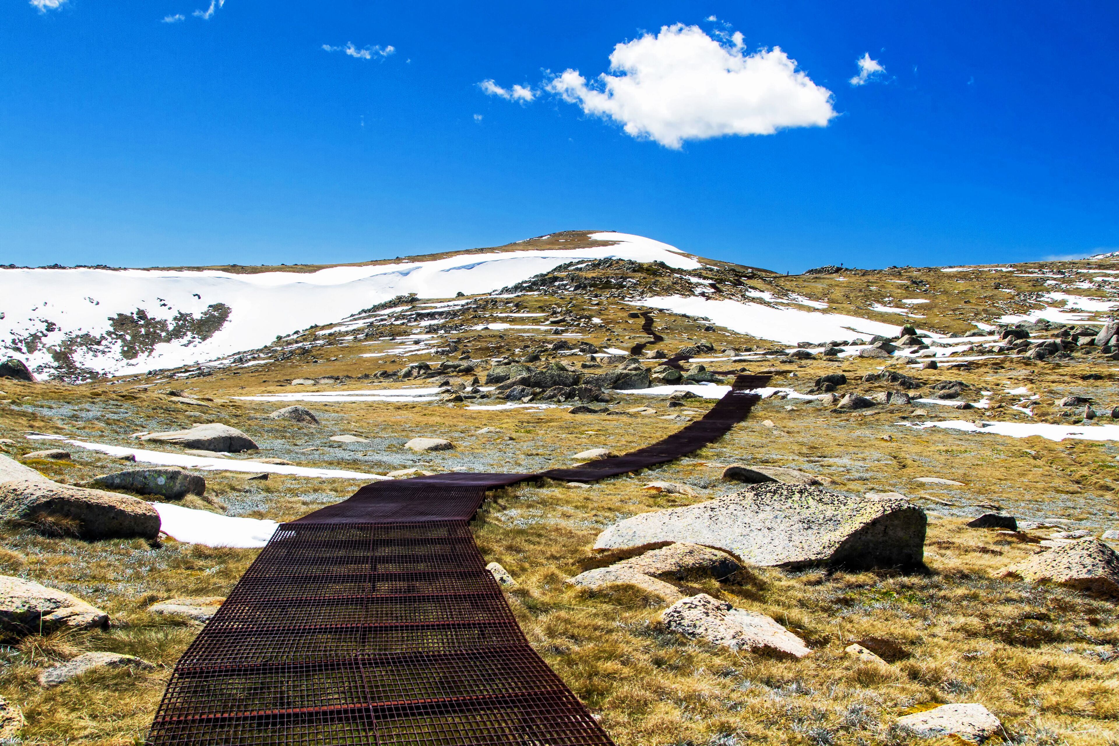 A snowy mountain landscape with a clear sky and a rope bridge.