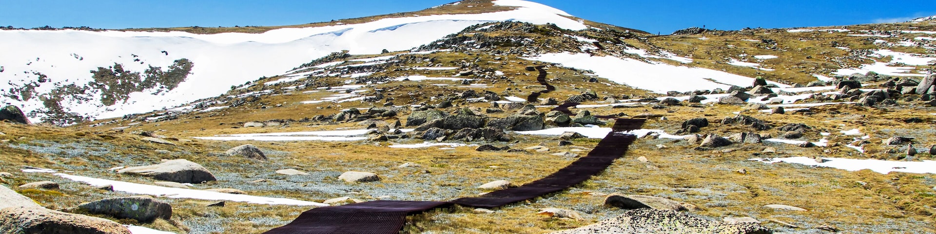 Un paysage montagneux enneigé, avec un ciel dégagé et un pont suspendu.