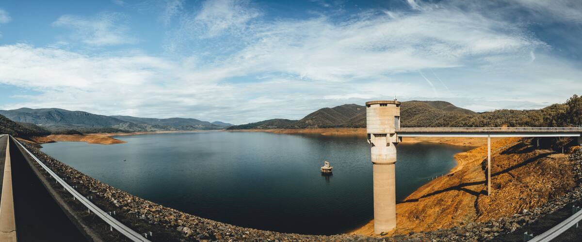 A bridge over a calm lake with mountains in the background.
