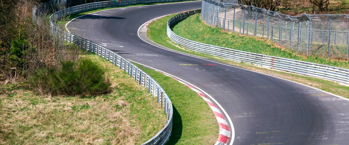 A winding race track with grassy areas and metal barriers.