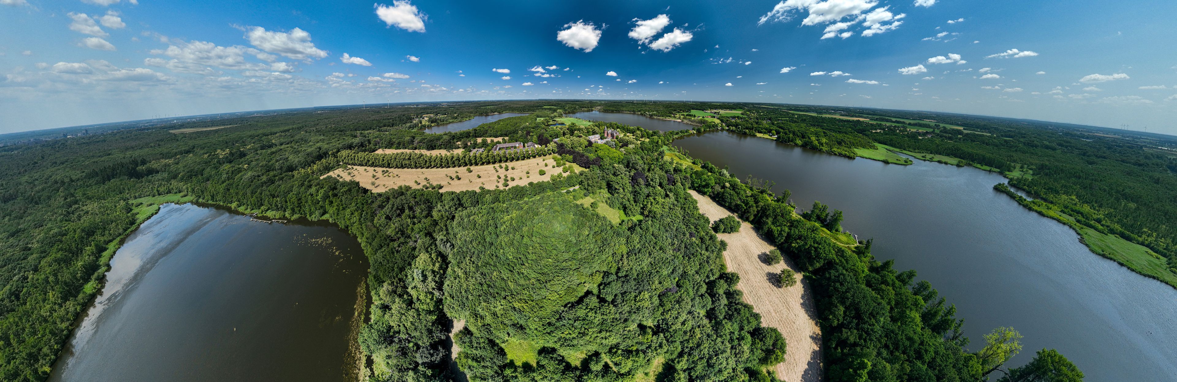 Ein weiter Blick über ein Flussdelta mit zahlreichen Wasserwegen, dichtem Wald und einer kleinen Siedlung.