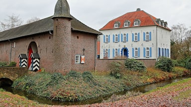 A historic building with a brick tower and a white facade with blue shutters.
