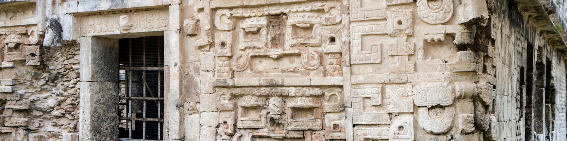 Una antigua estructura de piedra con intrincadas tallas y una pequeña ventana.