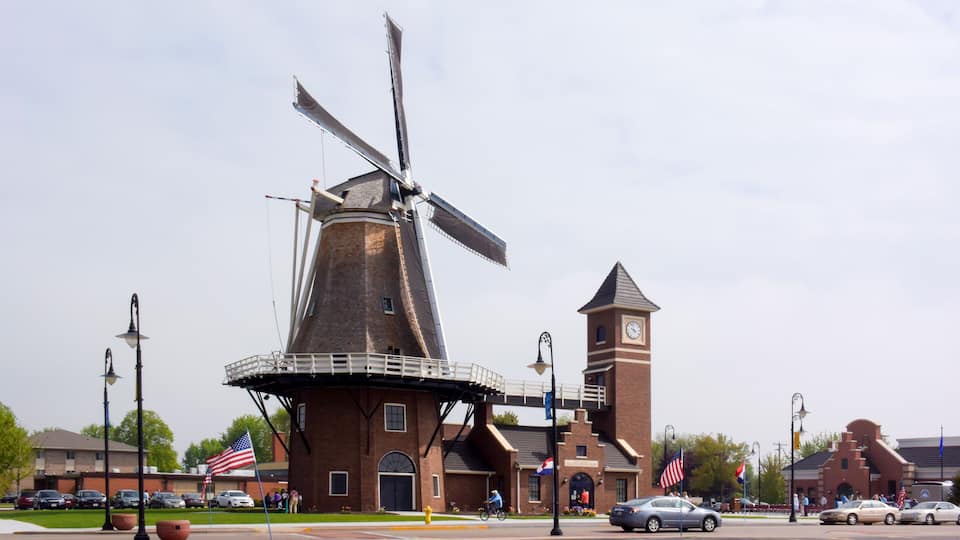 A windmill, a clock tower, and several cars on a street.