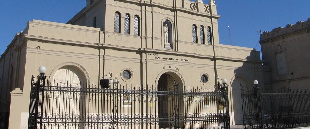 A historic building with a clock tower, statues, and arched windows.