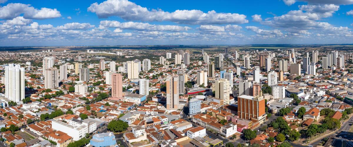 A cityscape with numerous high-rise buildings, a mix of residential and commercial structures, and a clear blue sky with scattered clouds.