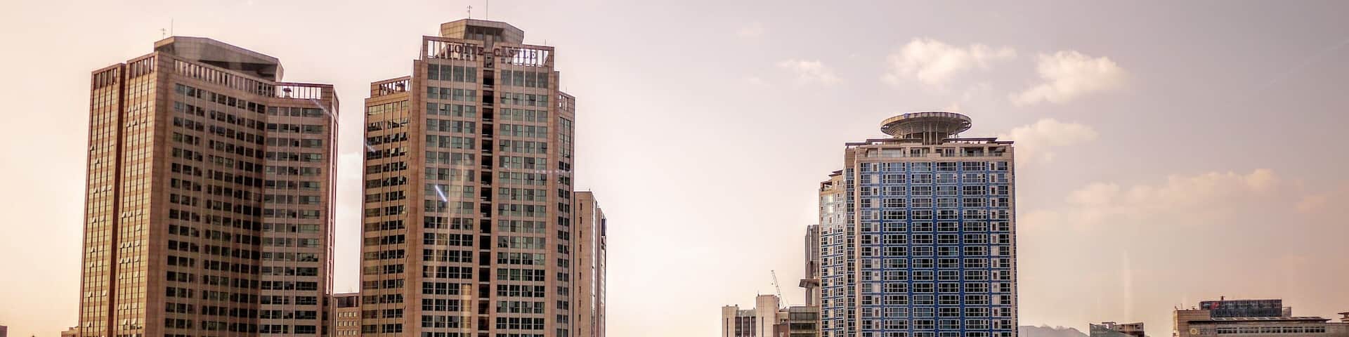 Un paisaje urbano con edificios altos, una calle concurrida y cielo despejado.