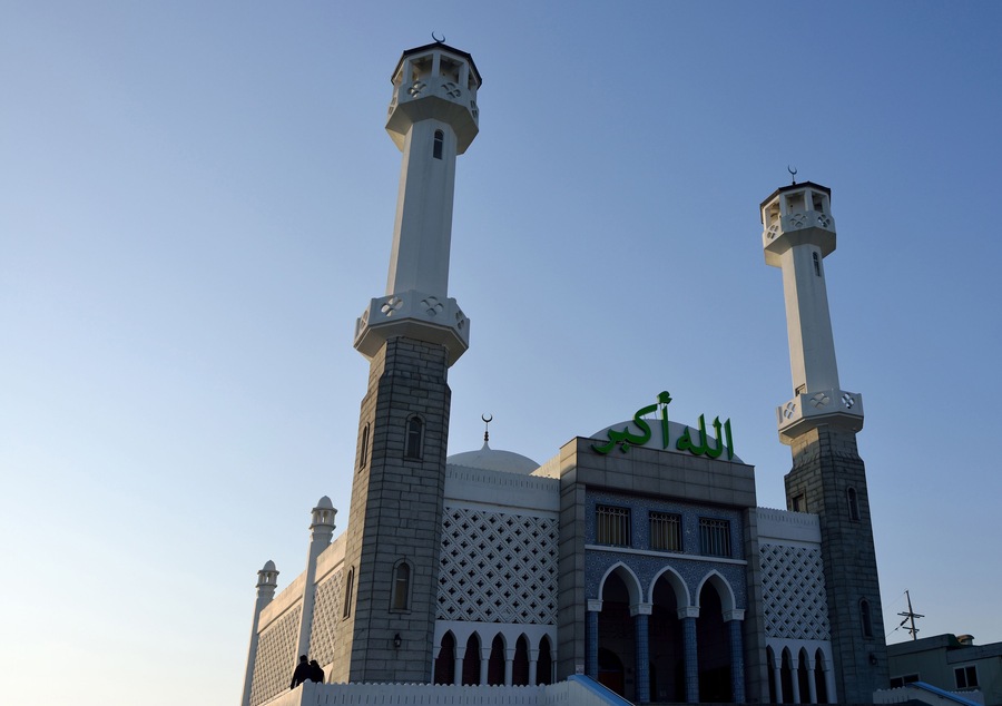 A mosque with two minarets and a dome, featuring Arabic calligraphy.
