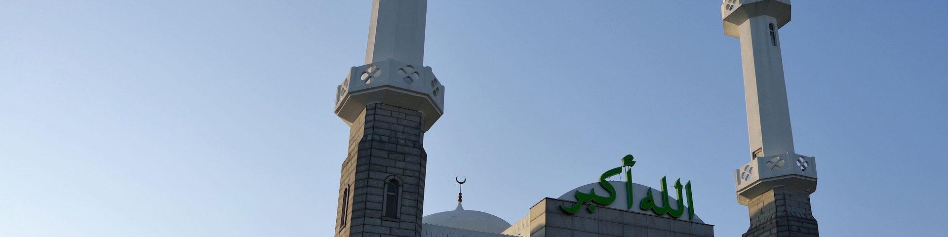 Una mezquita con dos minaretes y una cúpula, con caligrafía árabe.