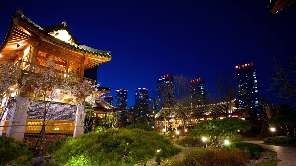 A traditional Korean pavilion with a tiled roof, surrounded by lush greenery and modern skyscrapers in the background.