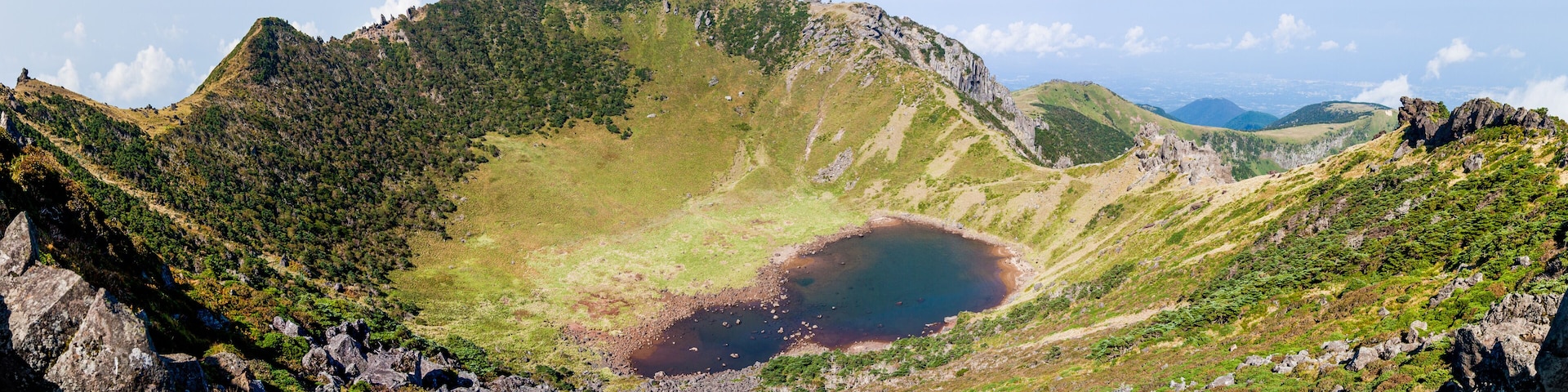 Un lago de cráter rodeado de montañas escarpadas y abundante vegetación.