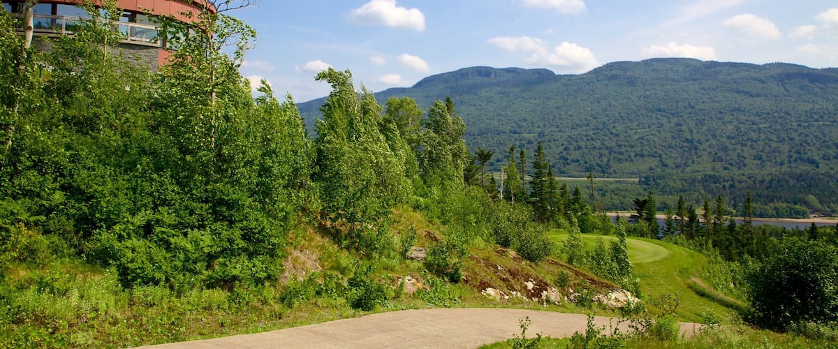 A lush green landscape with a winding road, a modern building, and a mountain range in the background.