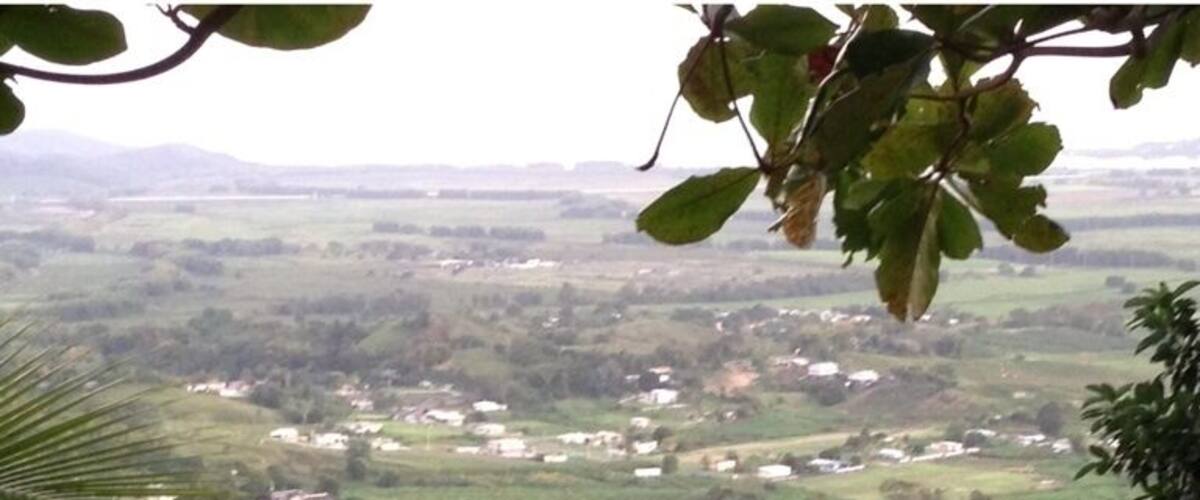 A lush valley with scattered houses amidst dense greenery and hills.