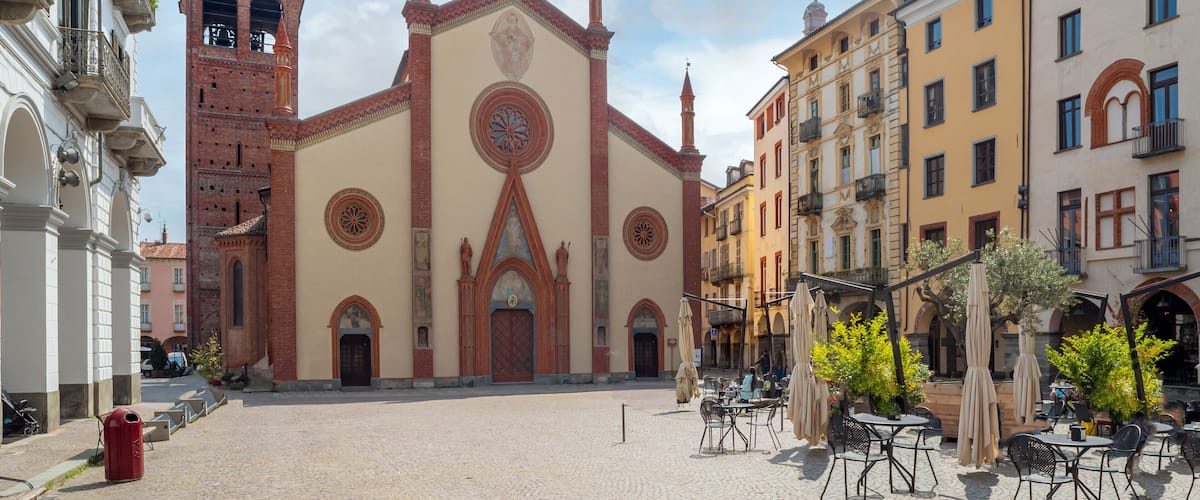 A historic church with a clock tower, cobblestone plaza, and surrounding buildings.