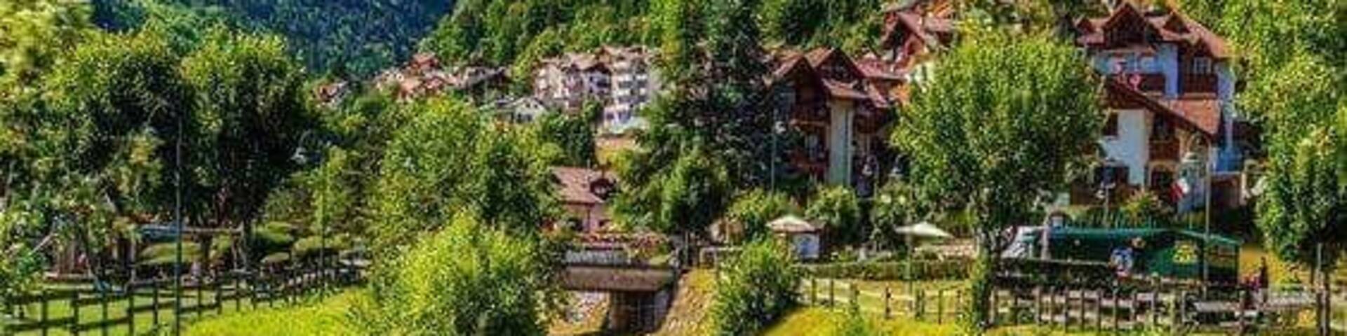 A mountain village with a cascading waterfall, lush greenery, and traditional houses.