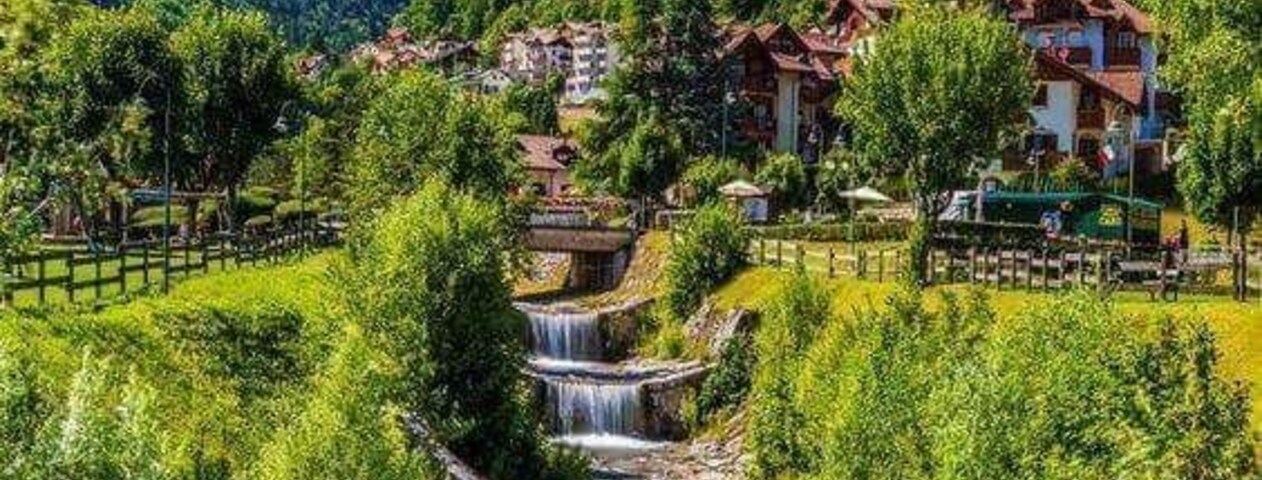 Un pueblo de montaña con una cascada en cascada, vegetación exuberante y casas tradicionales.
