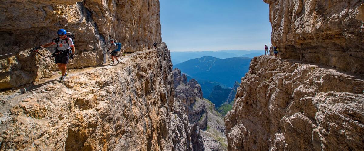 A rocky mountain path with hikers and a clear sky.