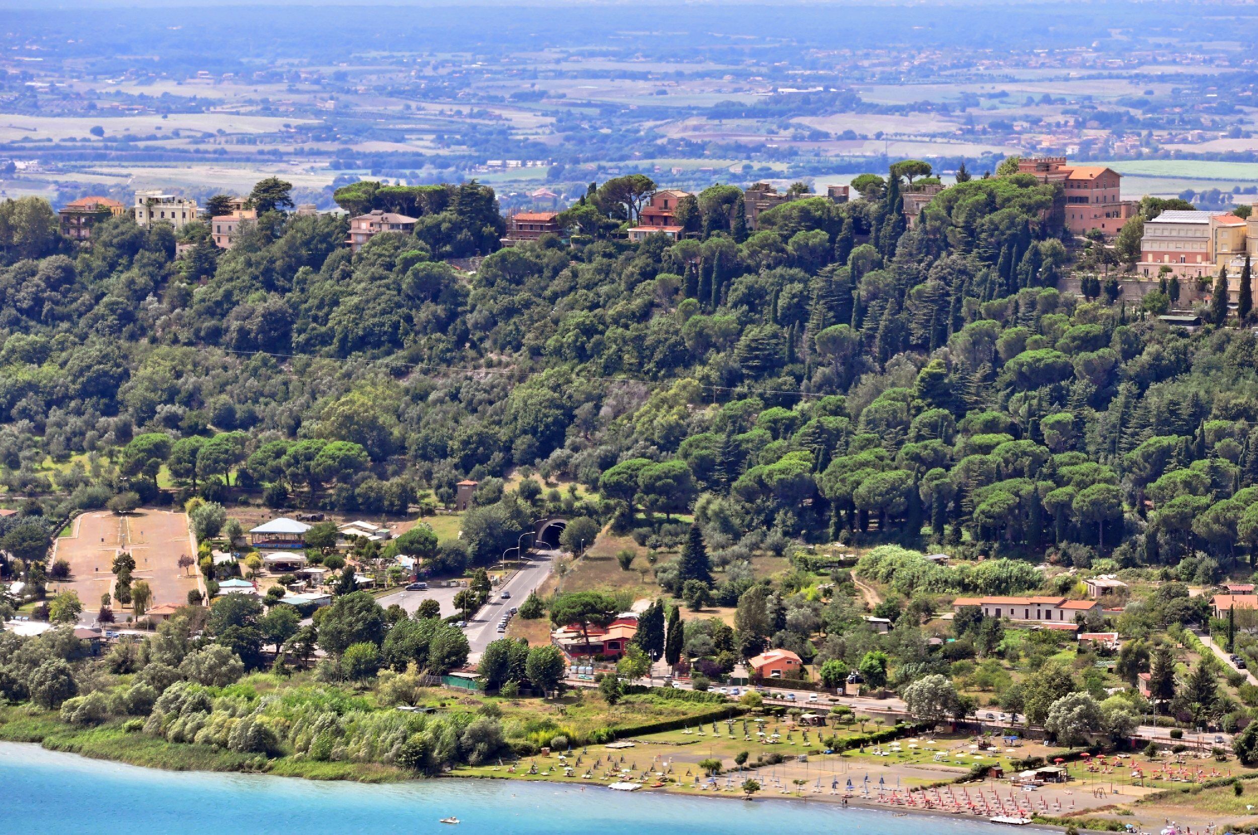 A coastal town with a hillside of buildings, a beach, and a clear view of the sea.