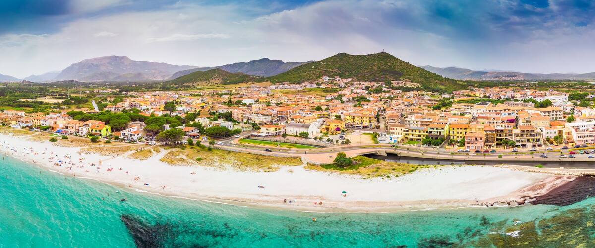 A coastal town with a beach, marina, and mountainous backdrop.