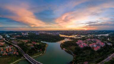 Vista panorâmica de uma cidade com rio, áreas verdes e edifícios modernos.