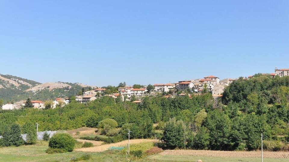 A hillside village with houses, greenery, and a clear sky.