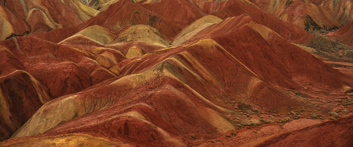 A landscape of colorful, rugged hills with a cloudy sky.