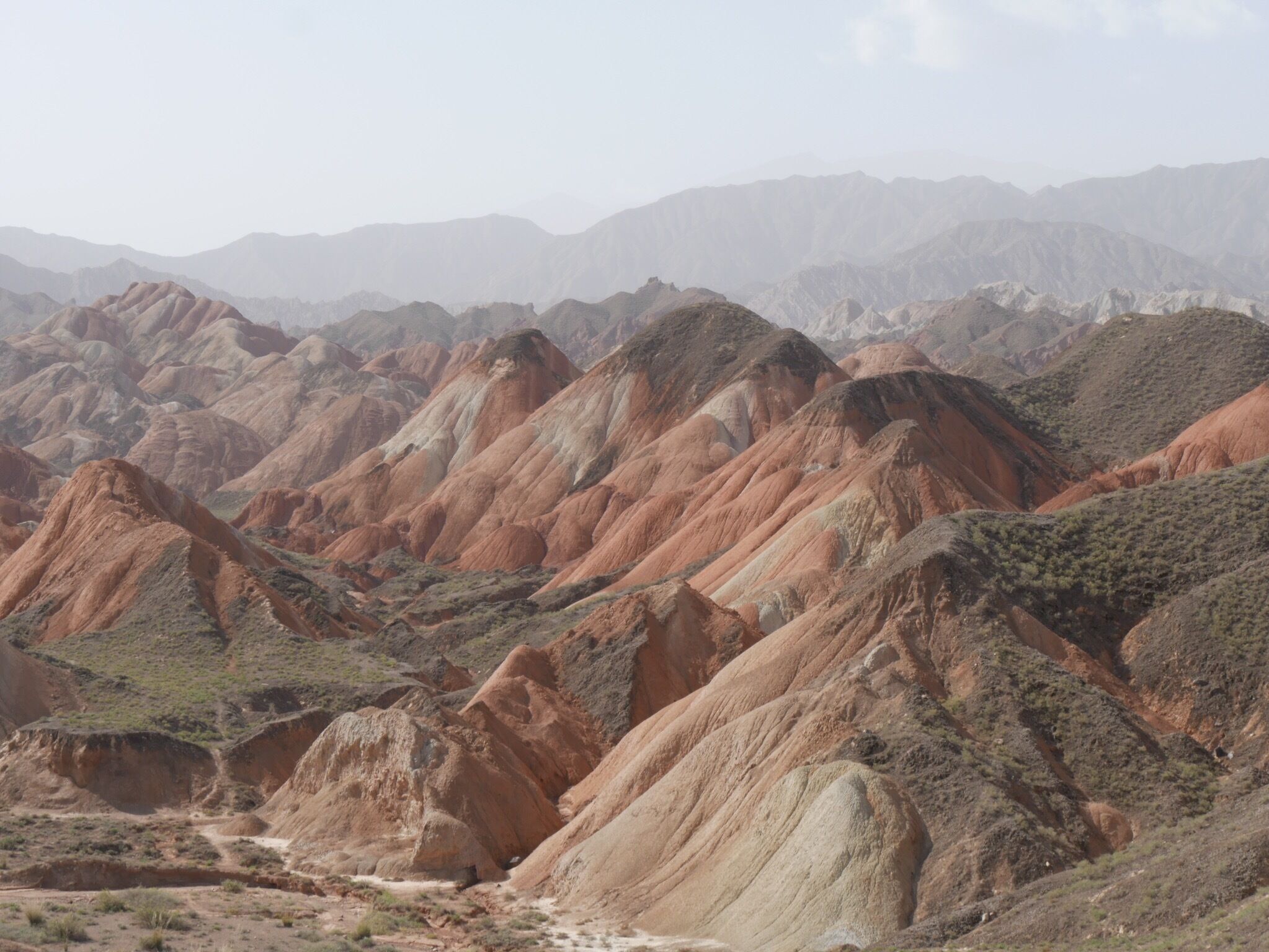 Zhangye National Geopark, the "Rainbow" or "Colorful" Mountains. About 30 minutes west of the city of Zhangye in the Gansu province of China. Buses from two park tourist centers ferry you to 4-6 stops within the park where you can climb up to various viewing platforms and walkways.