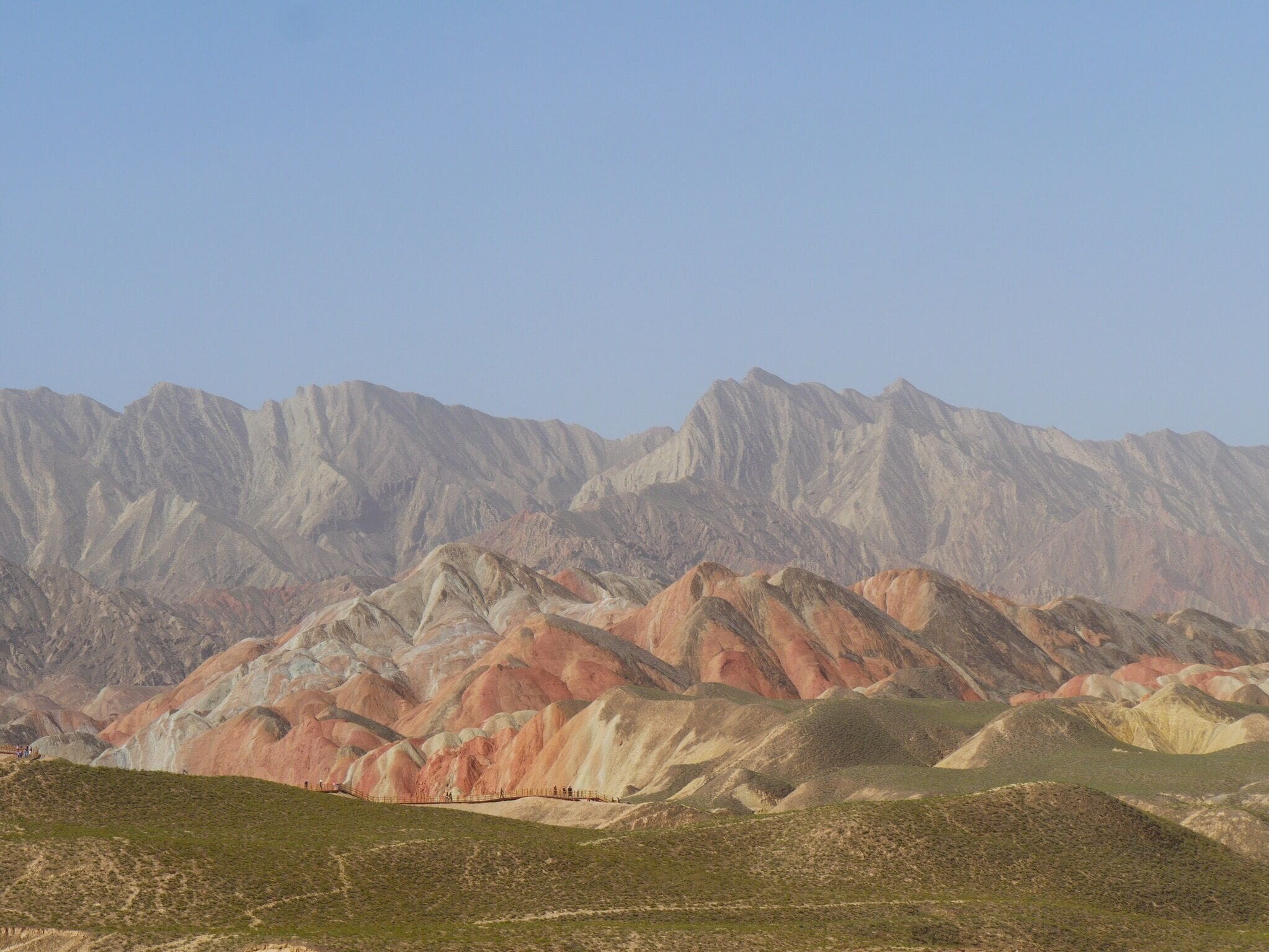 Zhangye National Geopark, the "Rainbow" or "Colorful" Mountains. About 30 minutes west of the city of Zhangye in the Gansu province of China. Buses from two park tourist centers ferry you to 4-6 stops within the park where you can climb up to various viewing platforms and walkways.