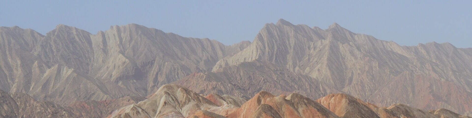 Zhangye National Geopark, the "Rainbow" or "Colorful" Mountains. About 30 minutes west of the city of Zhangye in the Gansu province of China. Buses from two park tourist centers ferry you to 4-6 stops within the park where you can climb up to various viewing platforms and walkways.
