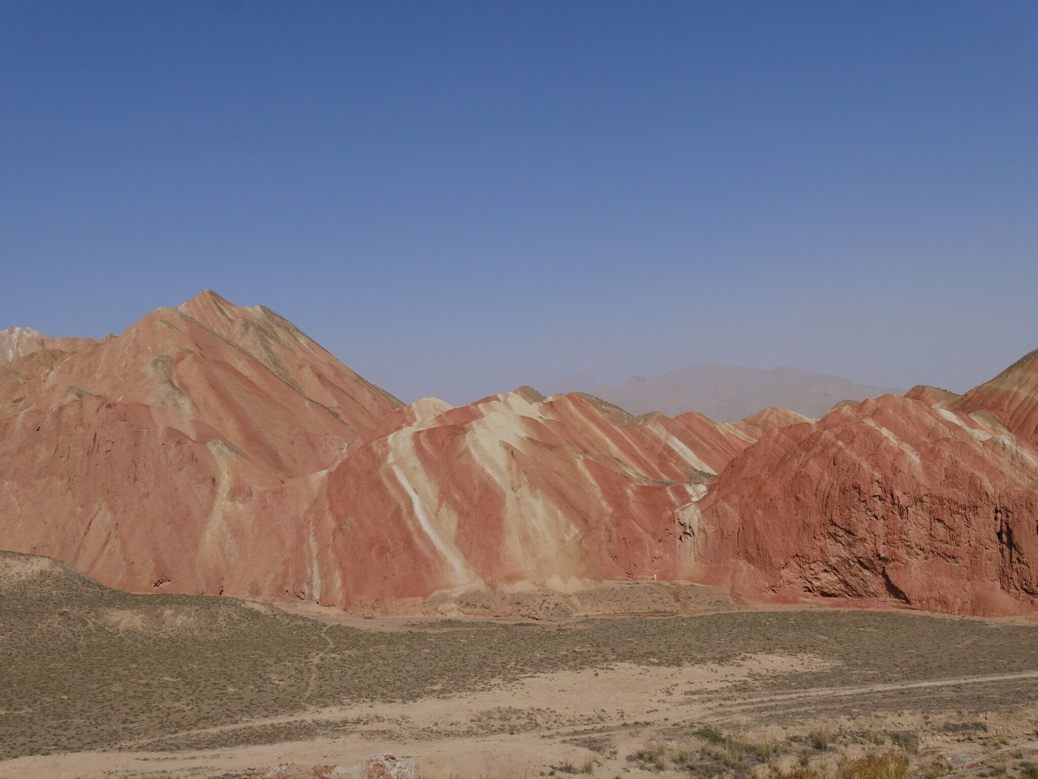 Zhangye National Geopark, the "Rainbow" or "Colorful" Mountains. About 30 minutes west of the city of Zhangye in the Gansu province of China. Buses from two park tourist centers ferry you to 4-6 stops within the park where you can climb up to various viewing platforms and walkways.