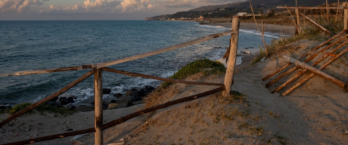 A beach with wooden fences and a rocky shoreline.