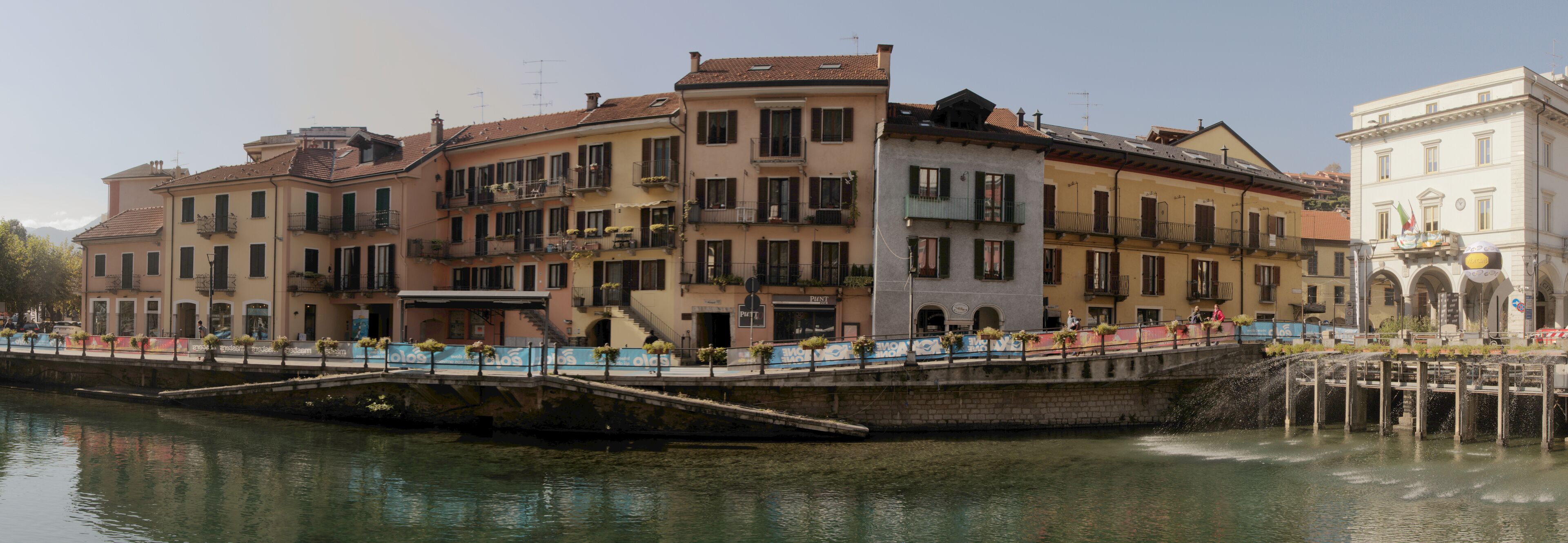 Un canal flanqueado por edificios y un puente con gente caminando.