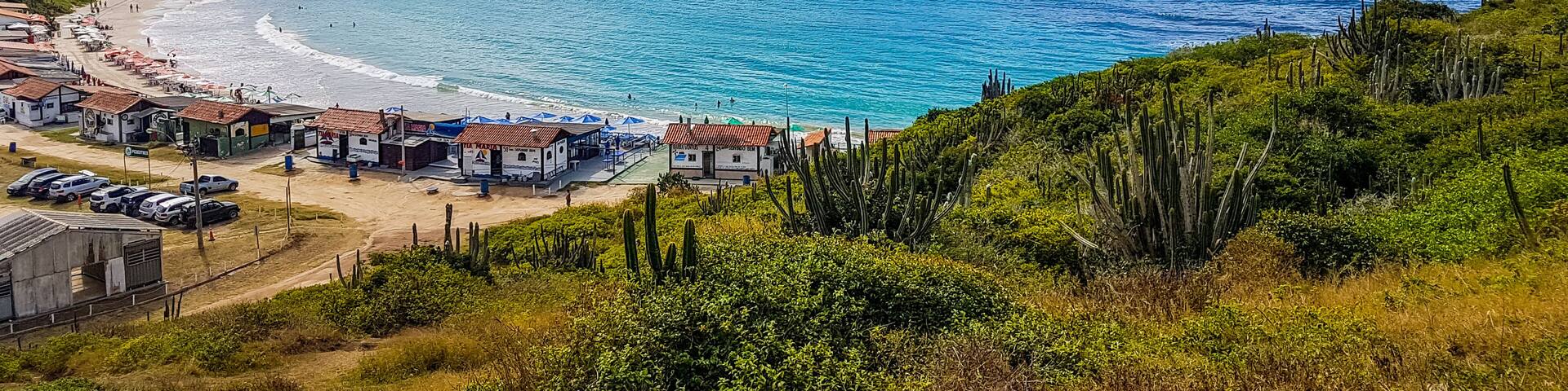 A coastal town with a beach, clear blue waters, and a mountainous backdrop.
