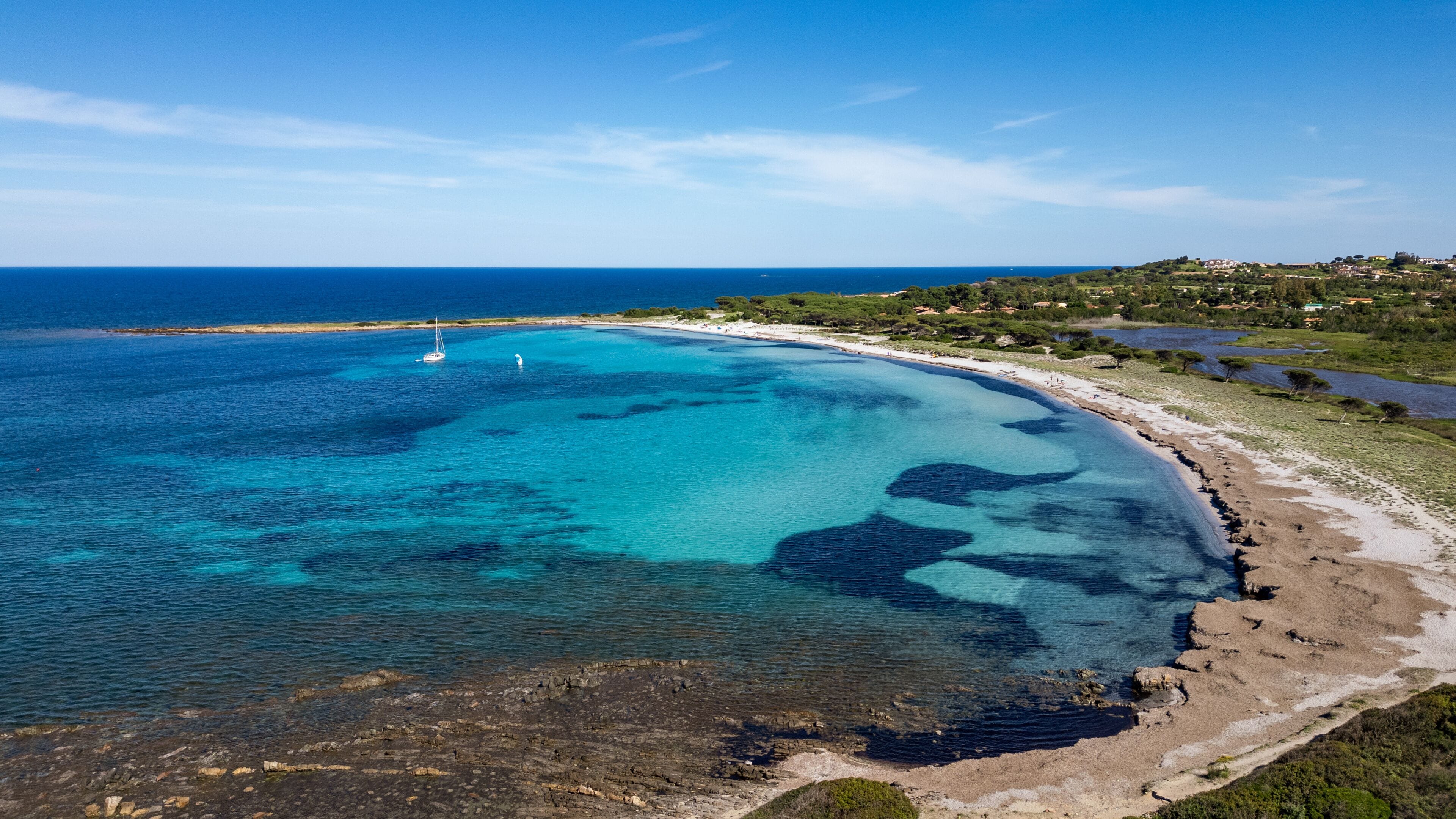 Aerial view of Porto Ainu beach with pine forest and crystal clear waters, Budoni, Sardinia.