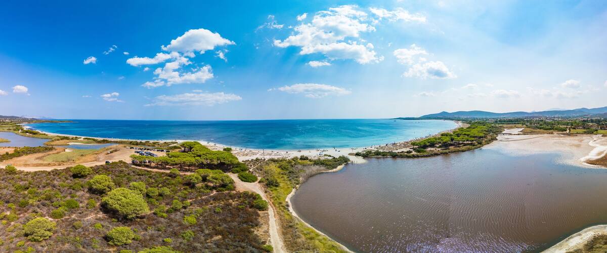 A coastal landscape with a beach, a river, and surrounding greenery.